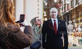 Een vrouw poseert woensdag op straat in Moskou bij een kartonnen versie van president en presidentskandidaat Vladimir Poetin.