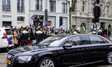 Koning Willem-Alexander vertrekt na de opening van het Nationaal Holocaustmuseum, zondag. Op de achtergrond demonstranten. 