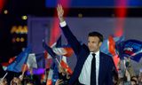 De Franse president Emmanuel Macron zwaait zondagavond naar aanhangers tijdens een bijeenkomst op de Champ de Mars in Parijs, na zijn herverkiezing voor een tweede termijn.