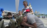 Een jongen pakt een gasmasker tijdens een herdenkingsdag in Kyiv voor de in de oorlog met Rusland overleden kinderen.