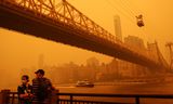 Rook van honderden bosbranden in het noorden van de Canadese provincie Quebec hangt over New York City, zoals hier bij de kabelbaan tussen Manhattan en Roosevelt Island. Mensen is aangeraden mondkapjes te dragen.