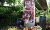 Een straatverkoper staat donderdag in Parijs naast verkiezingsaffiches van kandidaten van het linkse Nouveau Front Populaire (NFP). 