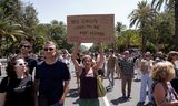 Een betoger houdt een bord omhoog met de tekst ‘Dit circus van vroeger mijn thuis’, zaterdag tijdens een demonstratie tegen massatoerisme in het Spaanse Malaga. 