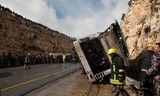 Reddingswerkers inspecteren op 16 februari 2012 de plek van de botsing tussen de vrachtwagen en de schoolbus met de Palestijnse kinderen.