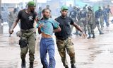 Een demonstrant wordt weggevoerd door politieagenten bij een oppositiebijeenkomst in een stadion in Conakry in 2009. Guinese militairen doden daar ten minste 157 mensen. 