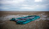 Een beschadigd bootje ligt eind oktober op het strand in het noord-Franse Gravelines, nabij Calais, na gebruik door een groep migranten bij een poging het Kanaal over te steken.  