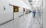 Een werknemer in een stofvrije ruimte, de cleanroom, waar de ASML-machines worden geassembleerd.