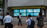 Voetgangers  lopen langs monitors waarop de Nikkei-index wordt weergegeven, afgelopen maandag in de Japanse hoofdstad Tokio.