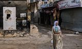 Een vrouw loopt op 8 februari door een beschadigde straat in Jenin op de bezette Westelijke Jordaanoever. 