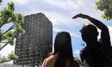 Mensen kijken naar de Grenfell Tower.