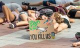 Jonge demonstranten houden een 'die-in' tijdens een mars tegen vliegreizen in München, 26 juli.