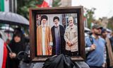 Een betoger in de Iraanse hoofdstad Teheran houdt zaterdag een ingelijste foto omhoog met daarop, van links naar rechts: de opperste leider Ali Khamenei, de vrijdag door Israël gedode Hezbollah-leider Hassan Nasrallah en de in januari 2020 door de VS gedode Iraanse topgeneraal Qassem Soleimani. 