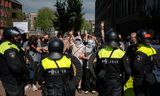 Leden van de mobiele eenheid  verdrijven demonstranten – met gezichtsbedekking – voor de ingang van de Universiteit van Amsterdam  op de Roeterseilandcampus in het centrum van de hoofdstad, in mei van dit jaar. Foto Bram Petraeus