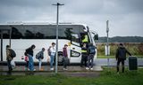 Vluchtelingen wachten op een pendelbus.