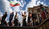 Een demonstrant houdt een Bulgaarse vlag omhoog tijdens een anti-regeringsdemonstratie in de Bulgaarse hoofdstad Sofia op 13 juli, waarbij het aftreden van premier Bojko Borissov werd geëist.