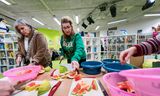 Ouders  en medewerkers van basisschool de Klaverweide in Almere snijden fruit voor om uit te delen in de klassen in het kader van EU Schoolfruit. 