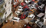 Bewoners beginnen met het schoonmaken van een straat in Valencia, na de overstroming van dinsdagavond. Foto Alberto Saiz / AP 