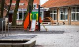 Een speeltoestel en een zandbak op een leeg schoolplein. 