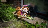 Exterieur van de dichtgespijkerde woning in Vlaardingen met daarvoor knuffels en bloemen voor het slachtoffer. 