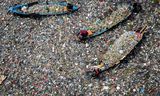 Mensen op boten halen recyclebaar plastic uit de zeer vervuilde rivier de Citarum in Bandung, West-Java. 