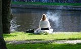 Een jonge vrouw rookt een e-sigaret aan de waterkant in Amsterdam. Tot het grote publiek wil het nog niet doordringen hoe schadelijk het is om te vapen, stellen artsen. Ook is het zeer verslavend.