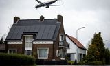 Een vliegtuig passeert woningen aan de Aalsmeerderdijk, terwijl het landt op de Aalsmeerderbaan van Schiphol. Hoewel vliegtuigen stiller zijn geworden, ervaren omwonende nog altijd veel geluidshinder. 