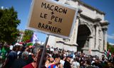 Een demonstrant houdt een bord vast met de tekst 'Macron + Le Pen = Barnier' tijdens een protest tegen de benoeming van de rechtse premier in Marseille Foto Christophe Simon/AFP 