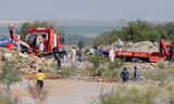 Reddingswerkers en politieagenten maandag bij mijnschacht 11 van de Buffelsfontein-mijn in Stilfontein, Zuid-Afrika.  