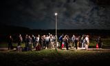 De opvanglocatie voor asielzoekers in Ter Apel was in september 2024 zo vol dat er alleen kwetsbare vluchtelingen worden binnen gelaten. Een groep mannen wacht 's avonds laat buiten op een oplossing. Foto Kees van de Veen 