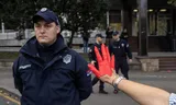 Een demonstrant toont haar rood geverfde hand aan een politieagent tijdens een protest naar aanleiding van het dodelijke ongeluk op een treinstation in de Servische stad Novi Sad. Foto Marko Djurica/Reuters 