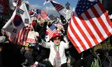 Aanhangers van de geschorste president Yoon zwaaien in Seoul met Zuid-Koreaanse en Amerikaanse vlaggen. Veel demonstranten geloven in complottheorieën over verkiezingsfraude. 