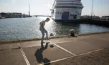 Een inwoner voetbalt bij het grote vluchtelingenschip Silja Europa aan de Marconistraat, Rotterdam. Het schip wordt gebruikt om vluchtelingen met verblijfsstatus in Nederland onder te brengen. 