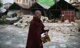 Een monnik tussen beschadigde huizen in Mandalay, de tweede stad van Myanmar, die bij de aardbeving van vrijdag zwaar is getroffen. 