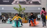 Chinese consumenten op schommelstoeltjes voor een Apple-store in Beijing. Foto Ng Han Guan/AP 