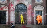 De deuren van het Koninklijk Instituut voor de Tropen (KIT) in Amsterdam, waar de CIDI-bijeenkomst plaatsvindt, worden door  demonstranten beklad met rode verf. Foto Dingena Mol/ANP  