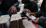 Valutahandelaren wisselen Amerikaanse dollars en Syrische lira’s om op straat in Damascus. Foto Louai Beshara/AFP 