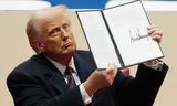 Donald Trump houdt een decreet omhoog op dag één van zijn presidentschap. Foto AP/Matt Rourke 