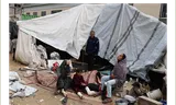 Een gewonde vrouw en kind zitten met anderen voor hun tent in Deir al-Balah op de Gazastrook.  