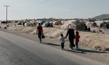 Langs de weg tussen Aleppo en Homs loopt een gezin naar het kamp waar ze al jaren wonen. Hun huis in het oostelijke deel van Aleppo is verwoest.