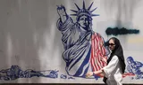 Een vrouw loopt langs een anti-Amerikaanse muurschildering vlak bij de voormalige Amerikaanse ambassade in Teheran.