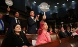 De Democratische afgevaardigde Jill Tokuda, in roze, houdt een protestbord omhoog tijdens de toespraak van Donald Trump in het Congres.  