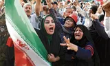 Een Iraanse vrouw houdt de nationale vlag omhoog tijdens een anti-VS- en anti-Israël-demonstratie in Teheran op 22 juni. Foto ABEDIN TAHERKENAREH/ EPA
