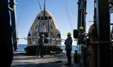 De SpaceX Dragon wordt aan boord van een SpaceX-schip gehezen na landing in de oceaan. Foto Keegan Barber 
