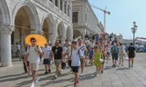 Toeristen op de kade bij het San Marcoplein in Venetië. Het stadsbestuur heeft de omvang van toergroepen beperkt. 