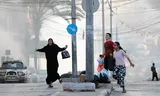 Een vrouw vlucht met haar zoon en dochter voor een luchtaanval in de buurt van het Al-Shifa-ziekenhuis in Gaza-Stad. November 2023.