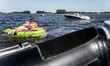Twee kinderen op een opblaasbare tube op het Sneekermeer worden getrokken door een motorboot. 