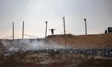 Amerikaanse huurlingen geven instructies aan Palestijnen die in de rij staan bij een GHF-voedselpunt.