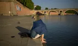 Een man gebruikt een paraplu tegen de zon aan de rivier de Garonne in Toulouse, Frankrijk.
