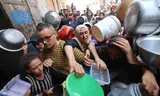 Palestijnen maandag bij een voedseldistributiepunt in Nuseirat, in de Gazastrook. Foto Eyad Baba/AFP  