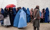 Taliban ziet toe op vrouwen in de rij voor voedseluitgifte, op 25 maart. 